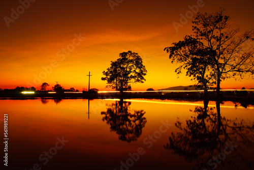 Silhouette trees beside the lake with light trails on the road during the dusk sky, Unseen landscape in Chiang Mai province northern Thailand. 