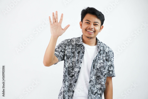 Positive cheerful asian man showing his open palm human emotions, facial expressions, handsome man waving his hand, hi, hello, see you later. isolated white background