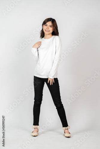 A young energetic woman wearing a white blank long sleeve shirt doing a pose