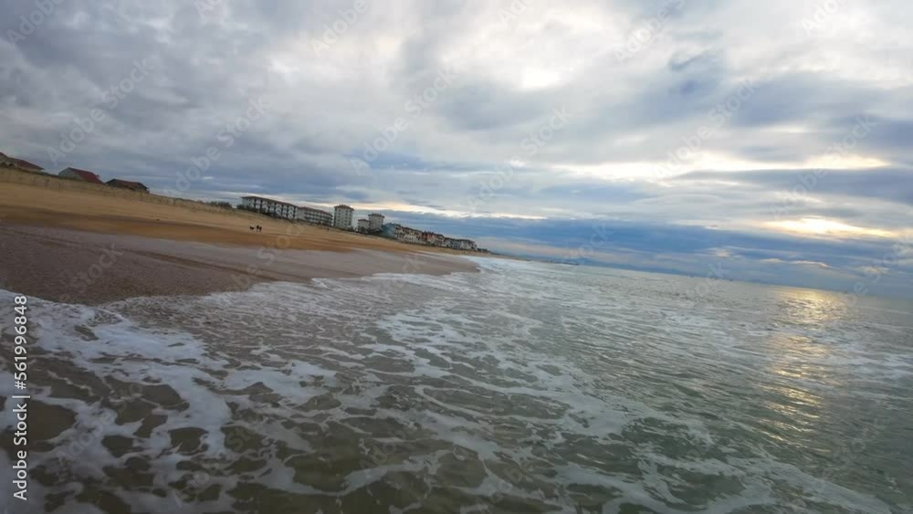 drone action flight over the waves at the surf beach of Hossegor during a cloudy sunset. Relaxing image in brown and blue tones