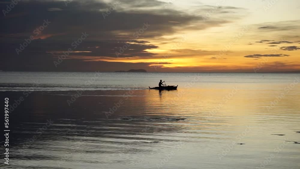A silhouette of a person kayaking while the sun is setting A silhouette of a person kayaking while the sun is setting