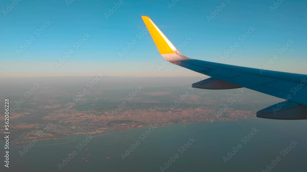 Airplane wing on the horizon line and the port on the way to Marseille with the ships in the sea Airplane wing on the horizon line and the port on the way to Marseille with the ships in the sea