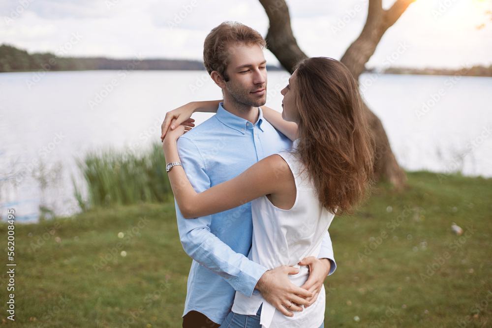 beautiful couple in love hugs standing on the river bank. beautiful couple in love hugs standing on the river bank.