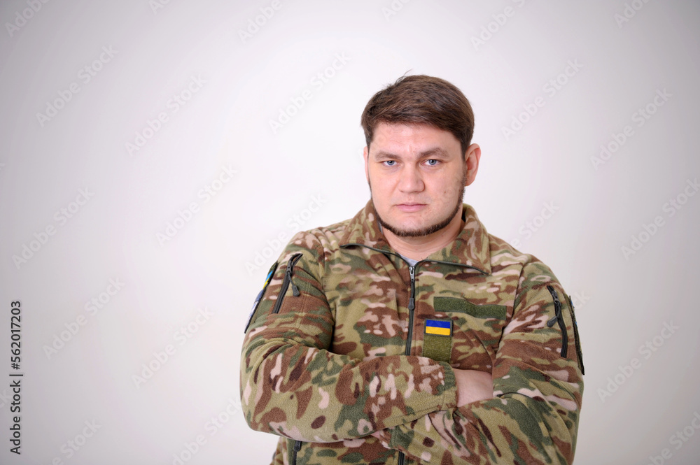 Ukrainian defender. soldier Armed Forces of Ukraine. A close-up photo of a military man blue eyes masculine chin beard neat stern look badge and flag of ukraine patch on uniform