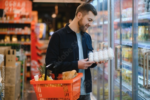 Φωτογραφία Handsome man buying some healthy food and drink in modern supermarket or grocery store