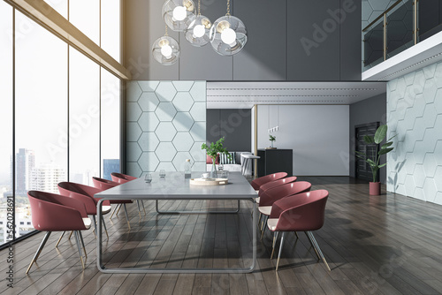 Leinwand Poster Side view on meeting table surrounded by red chairs on dark wooden floor in sunlit spacious conference hall with polygonal print walls background and city view from panoramic window