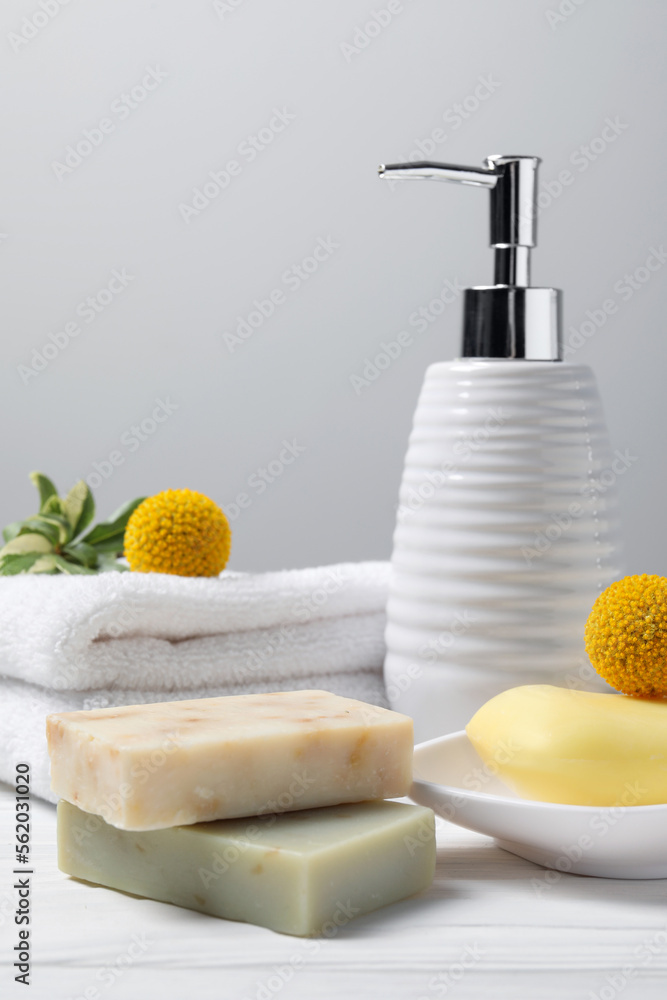 Soap bars, bottle dispenser and towels on wooden table against white background Soap bars, bottle dispenser and towels on wooden table against white background