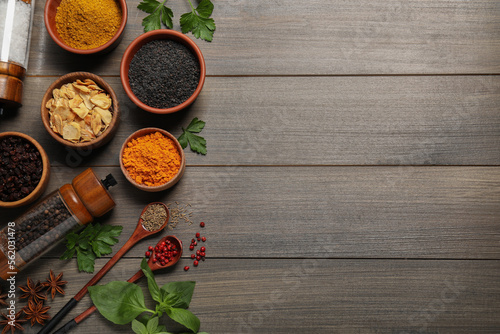 Flat lay composition with different spices on grey wooden table. Space for text