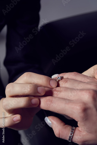 Cropped close-up shot of a woman putting engagement ring on finger of lesbian girlfriend in room. LGBT concept. Female relationship.