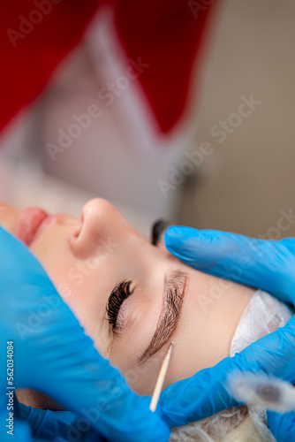 Markup with Wooden Stick on eyebrows of young woman while permanent make up.