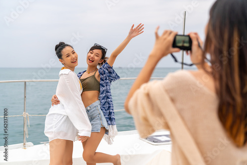 Group of Attractive Asian woman friends using digital camera photography together while travel on luxury private catamaran boat yacht sailing in the ocean on summer holiday vacation at tropical island © CandyRetriever 
