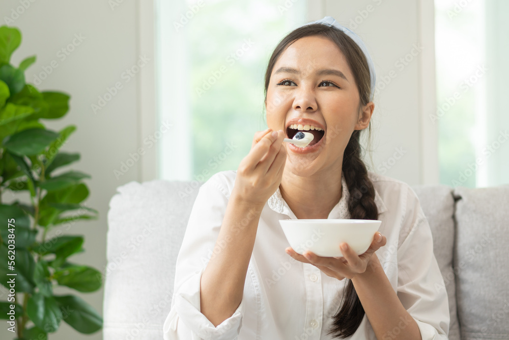 Healthy lifestyle, wellness food asian young woman hand use spoon eat tasty fresh organic yogurt, dairy product in bowl breakfast meal at home. Snack tasty on diet nutrition delicious natural yoghurt Healthy lifestyle, wellness food asian young woman hand use spoon eat tasty fresh organic yogurt, dairy product in bowl breakfast meal at home. Snack tasty on diet nutrition delicious natural yoghurt
