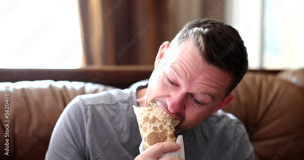 Young man eating delicious appetizing shawarma at home 4k movie slow motion Young man eating delicious appetizing shawarma at home 4k movie slow motion