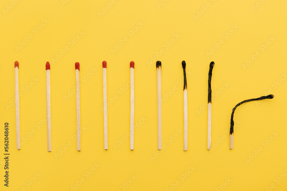 Evolution of matches from new to completely burnt on a yellow background as a symbol of aging or burnout Evolution of matches from new to completely burnt on a yellow background as a symbol of aging or burnout