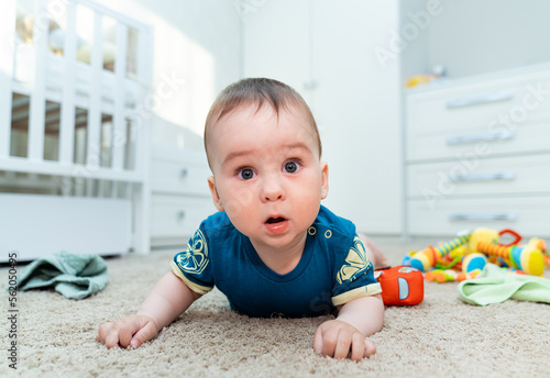 Baby boy with his first toys. Cute little boy lies on his stomach with emphasis on his hands.