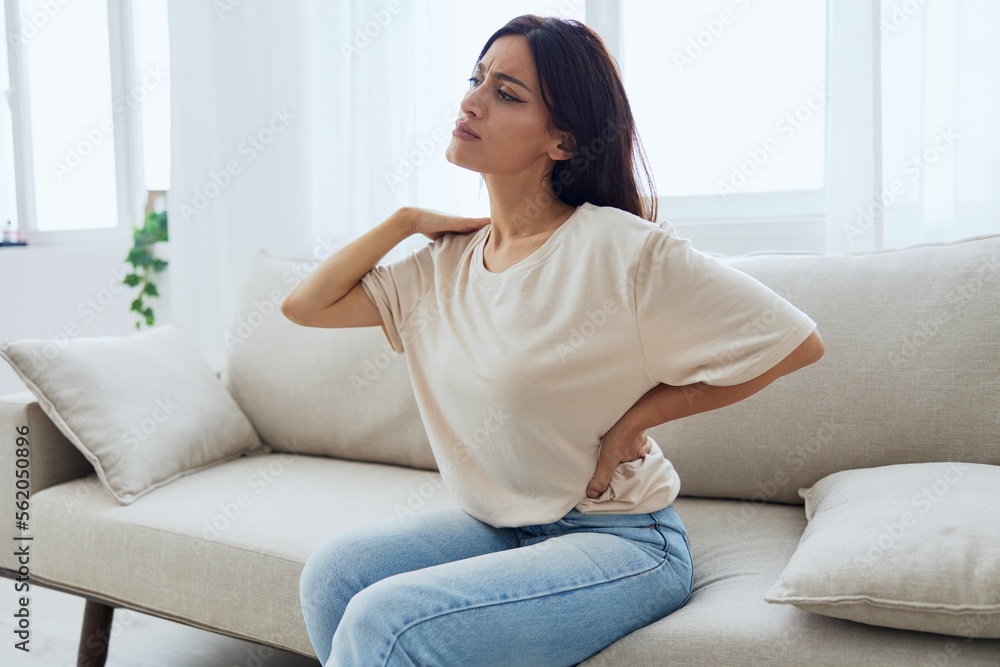 Woman sitting on sofa at home back and lower back pain, protrusion, back  problems after 30 years Stock-Foto | Adobe Stock