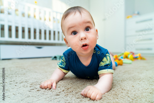 Baby boy with his first toys. Cute little boy lies on his stomach with emphasis on his hands.