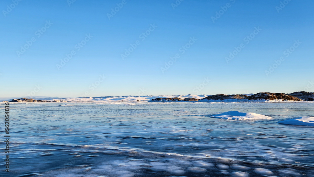 Winter sea sunset. Panoramic view of the snow-covered shore of the frozen sea, the lake at sunset. Shards of ice close-up. Christmas, seasons, winter.  Selective focus.