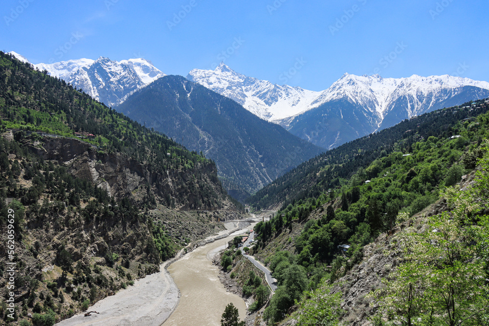 Naklejka premium A valley with green and snow capped mountains with a river