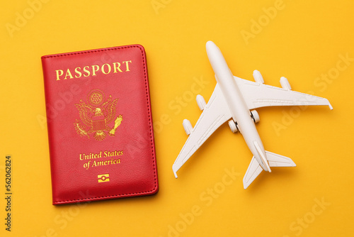 American passport and toy plane on a colored yellow background, a concept on the theme of traveling to America