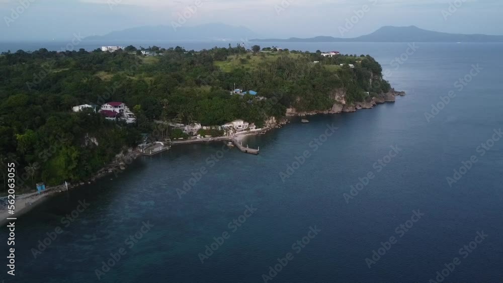 Rocky coast of a tropical island. A small fishing village by the sea and a large hotel building. Motor boat near the pier. Rocky coast of a tropical island. A small fishing village by the sea and a large hotel building. Motor boat near the pier.