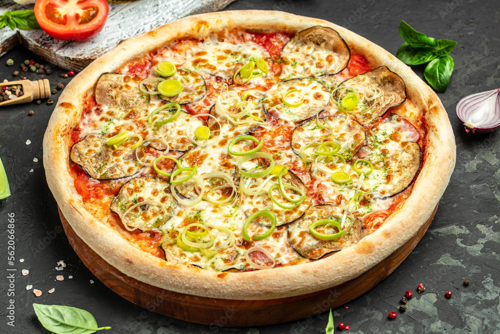 vegan pizza with eggplant, tomatoes and leeks on a dark background, banner, menu, recipe place for text, top view