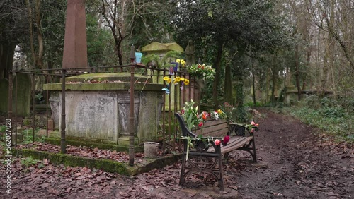 Gravestone decorated with flowers in remembrance of a loved one, covered in moss in a forest graveyard on a cloudy day photo