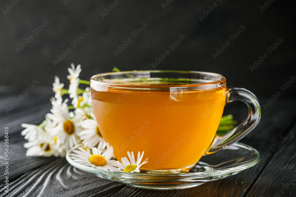 aromatic hot chamomile tea on a black rustic wooden background aromatic hot chamomile tea on a black rustic wooden background