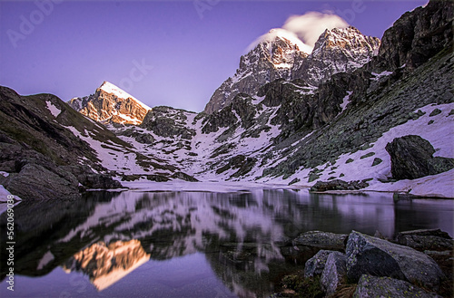 Alpine lake with snow-capped mountains (Monviso, 3841 m) reflected in its waters at sunset. Clear blue sky. Italian Alps - Fiorenza Lake, Monviso Park. Spring thaw. photo