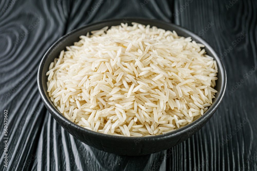 raw basmati rice on a black wooden background raw basmati rice on a black wooden background