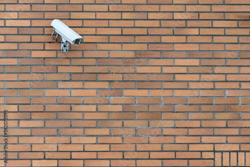 CCTV cameras are installed on the brick wall at the entrance to the supermarket. Security and anti-theft systems. A surveillance camera and an armored window in the bank.