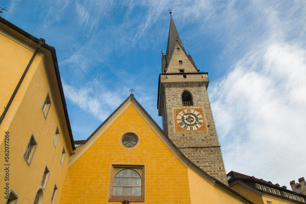 View of bell tower with clock in the historic center of Brunico town in Alto Adige, Italy