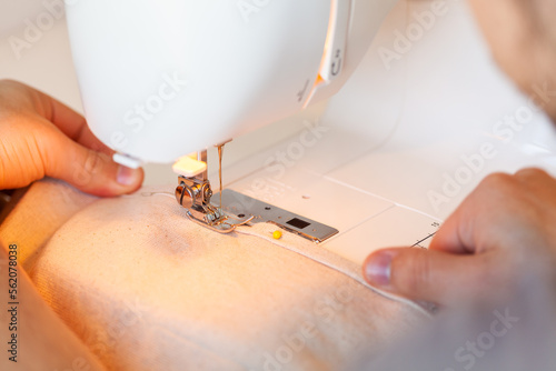 Young mans hands feeding canvas fabric through sewing machine photo