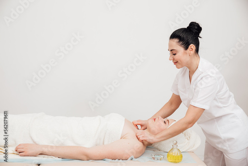 makes a spa massage for a woman in the face and neck photo