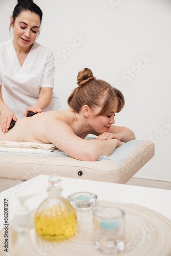 masseur does spa massage of the back of a woman with stones