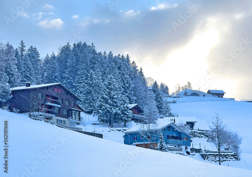 Old traditional swiss rural architecture and alpine livestock farms in the winter ambience over the Lake Walen or Lake Walenstadt (Walensee) and in the Swiss Alps, Amden - Switzerland / Schweiz