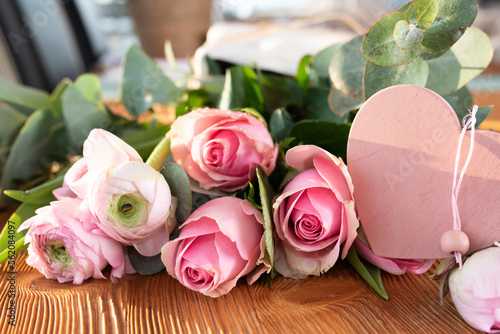 Pink roses and ranunculus with heart shape for mothers day. Background with short depth of field for love greetings. 