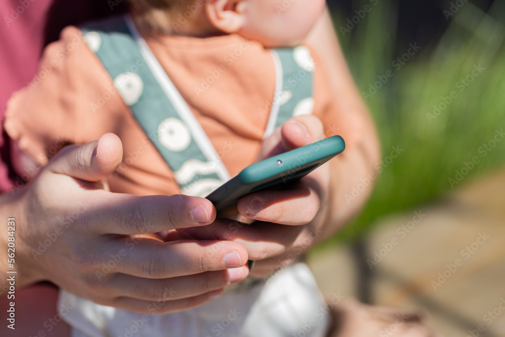 focus on mobile phone with dad holding baby behind focus on mobile phone with dad holding baby behind