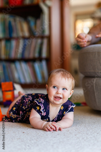 Baby on floor of library room with cheeky grin photo