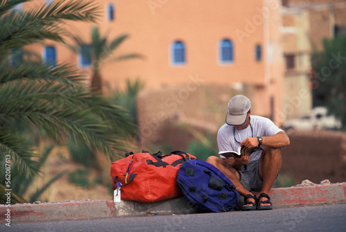 A  male traveler waiting for a ride in a foreign country.