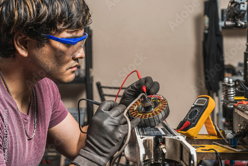 Mechanic using a multimeter to check the  voltage of a  scooter