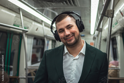 man young male caucasian passenger one person positively cheerful listens to music in headphones, smiles and go by subway transport in the morning. concept subscription to music.