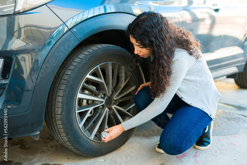 Murais de parede Woman checking the car tires