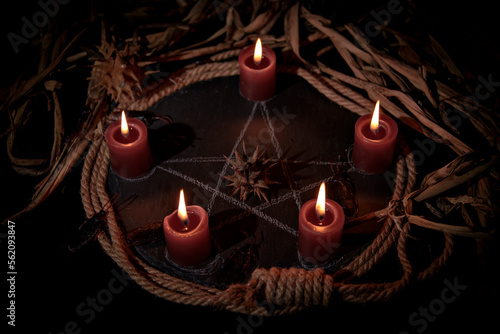 Voodoo doll, black candles, pentagram and old books on witch table. Occult, esoteric, divination and wicca concept. Mystic, voodoo and vintage background.
