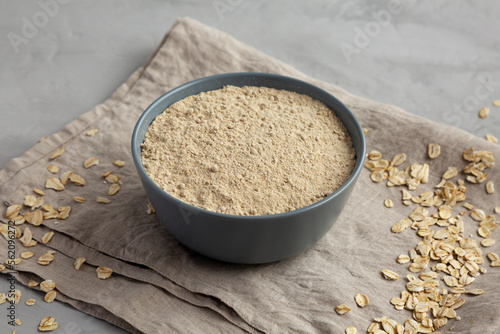 Organic White Oat Flour in a Bowl on a gray background, side view.
