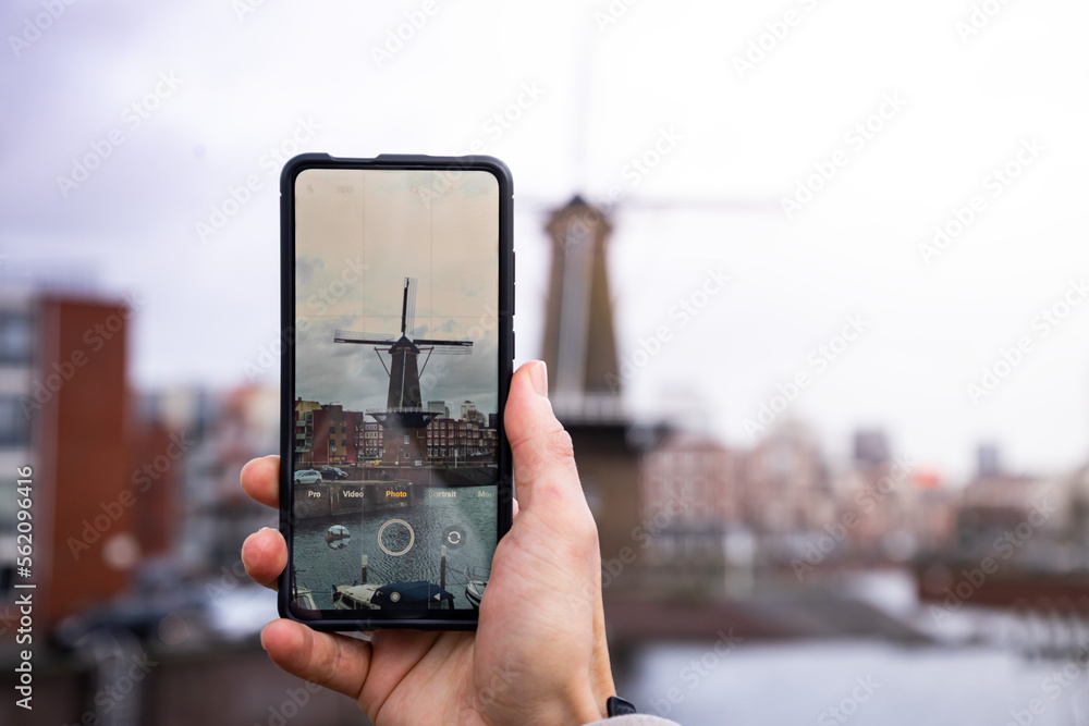 Ein Bild von einem Smartphone beim Fotografieren einer Windmühle in Rotterdam