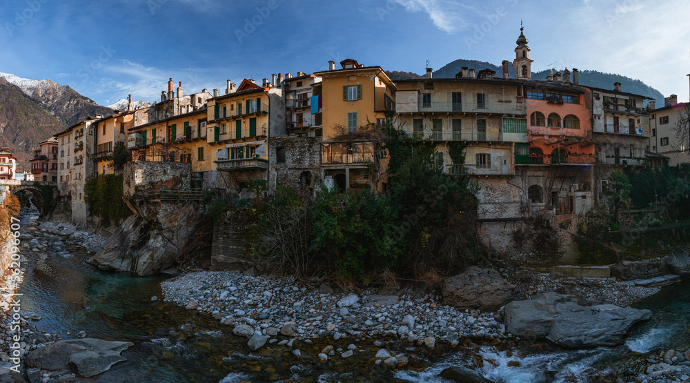 The riverside of the town of Chiavenna (Lombardy, Italy) with its historic houses and the mountains in the background, during a winter afternoon - January 2023.