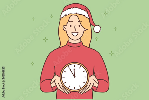 Smiling woman in Santa hat hold clock
