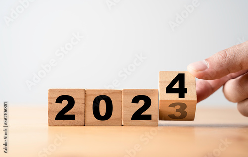 Hand flipping wooden block cube change from 2023 to 2024 for preparation new year change and start new business target strategy concept.