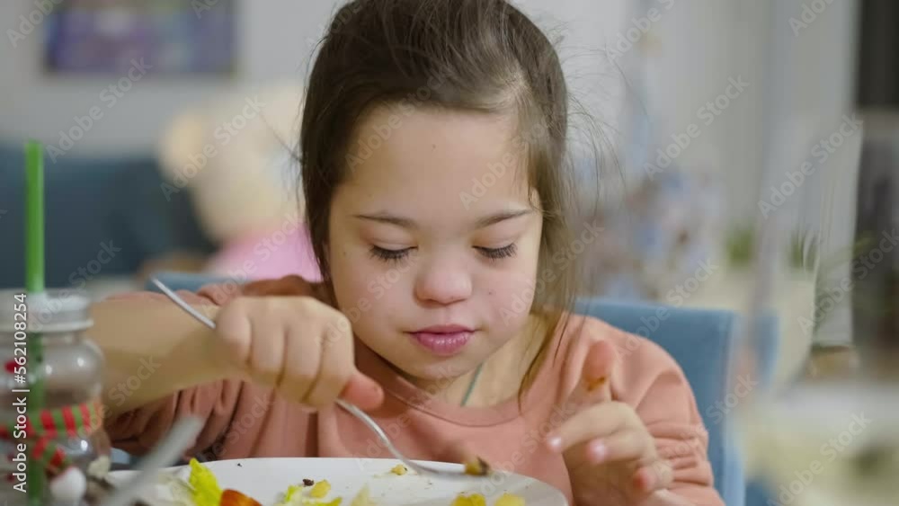 A Child With Down Syndrome Is Eating From A Plate a Cute Girl A a-child-with-down-syndrome-is-eating-from-a-plate-a-cute-girl-a